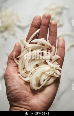 Julienne cuted onions on mans hand. Photo show how does julienne sliced or pole to pole to root to stem or half rings onions look like Stock Photo