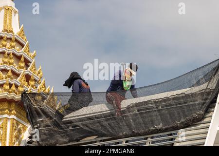 Men build a new roof at a Buddhist temple - Wat Pho Thong, Bangkok, Thailand Stock Photo
