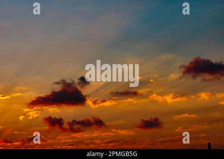 Sun rays through the clouds at sunset. Partly cloudy sky. Dramatic cloudscape. Stock Photo