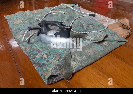 Old iron with ironing cloth on wooden floor Stock Photo