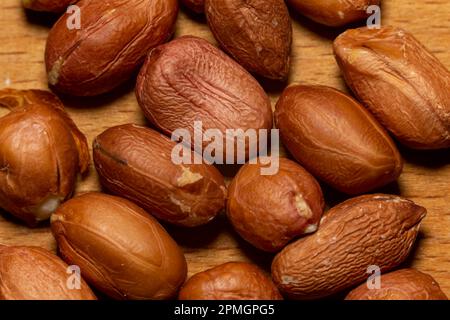 Raw unpeeled peanuts on kitchen board, extreme close-up macro view Stock Photo