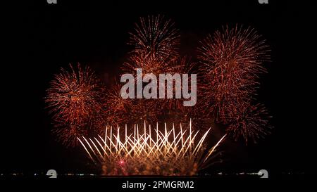 Abstract colored real firework background with big shining glowing fireworks show with bokeh lights in the night sky. Stock Photo