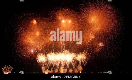 Abstract colored real firework background with big shining glowing fireworks show with bokeh lights in the night sky. Stock Photo