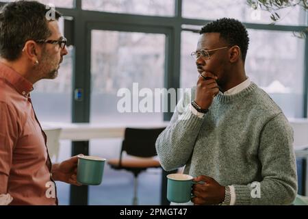 Two diverse coworkers making a plan for their next client on the internet at the office Stock Photo