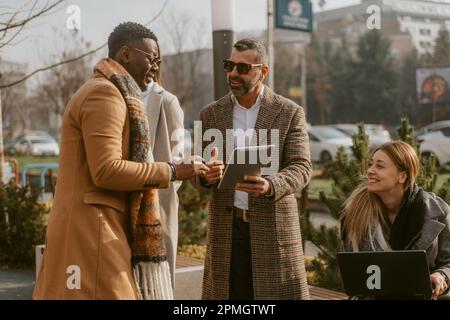 Four business colleagues smiling and working together at the park Stock Photo