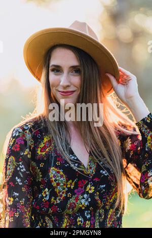 A portrait of a young smiling woman in a wide-brimmed hat looks at the camera. Stock Photo