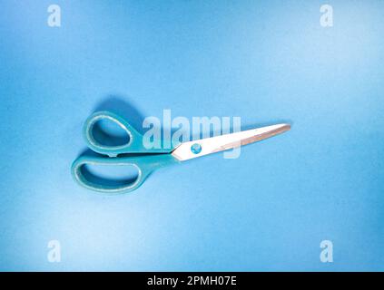 single pair of blue handled scissors isolated on a blue background Stock Photo