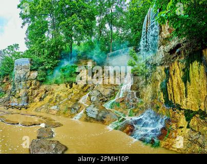 The waterfall on the rocky cliff edge among the lush greenery of English Landscape Garden in Sofiyivsky Park, Uman, Ukraine Stock Photo