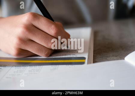 Kid affected by dyslexia doing homework, writing, reading notebook task using colorful overlay strip. Education, learning disability, reading Stock Photo