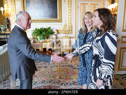 King Charles III greets Royal Mint CEO Anne Jessopp (centre) and Director Rebecca Morgan (right) before being presented with newly minted Coronation coins at Windsor Castle, Berkshire. A crowned portrait of the King will for the first time feature on a new range of commemorative coins created to celebrate the upcoming coronation. The collection, which includes a 50p and £5 coin, will be released later this month ahead of the historic May 6 celebration. Picture date: Thursday April 13, 2023. Stock Photo
