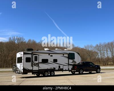 A truck pulling a fifth wheel trailer take a break at a rest area along the interstate after a winter down south. Stock Photo