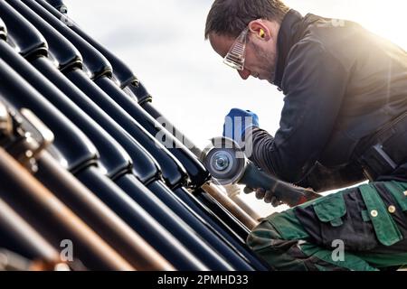 Craftsman using an angle grinder on a tiled roof Stock Photo