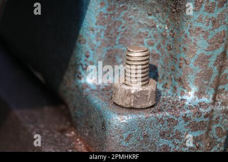 Mild steel nut and bolt are fitted on a cast iron engine block base. Fastener with a view of threads Stock Photo