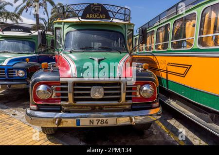 Another restored vintage Bedford bus, painted red and green with the ARUCAD lettering on its roof rack, stands beside a green-and-orange bus from the same fleet on the campus of the Arkin University of Creative Arts and Design in Kyrenia (Turkish: Girne), Turkish Republic of Northern Cyprus (TRNC). The British commercial-vehicle brand Bedford, founded by Vauxhall Motors in 1931, built such vehicles until the 1980s. Founded in 2017 by the Arkın Group, the university is a thematic institution dedicated exclusively to art, design and communication. Stock Photo