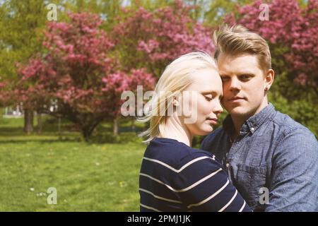 young couple in love hugging in nature during cherry blossom in park Stock Photo