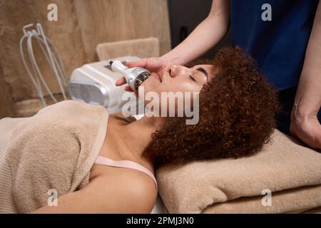Side view faces of a young lady, who is undergoing an RF lifting procedure Stock Photo