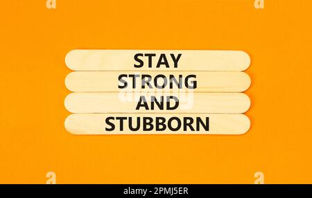 Stay strong and stubborn symbol. Concept words Stay strong and stubborn on wooden stick. Beautiful orange table orange background. Motivational busine Stock Photo