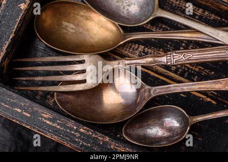 Vintage rectangular shabby wooden box with spoons and forks on a dark concrete background Stock Photo