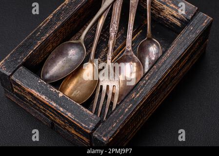 Vintage rectangular shabby wooden box with spoons and forks on a dark concrete background Stock Photo