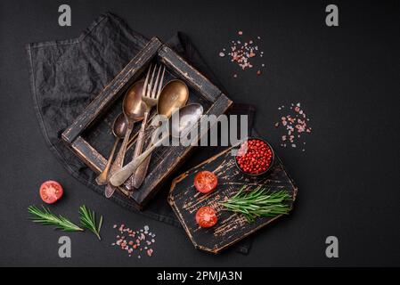 Vintage rectangular shabby wooden box with spoons and forks on a dark concrete background Stock Photo