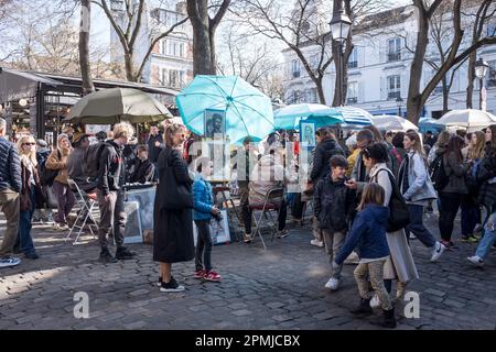Visitors walk by the artists and artworks in the Spring sunshine, Place du Tertre, in Montmartre, in Paris, France Stock Photo