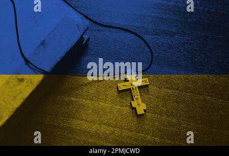 Cross on the background of the Ukrainian flag. Pray for Ukraine, flag Ukraine. Russia vs Ukraine stop war. Stock Photo
