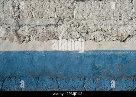Old limewashed white wall with blue skirting board and flacking paint, rustic background of traditional rural architecture in La Mancha, Spain Stock Photo