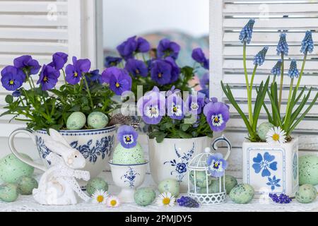 easter arrangement with blue spring flowers in cups, easter eggs and easter bunny Stock Photo
