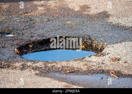 A dep pothole in asphalt parking lot filled with water Stock Photo