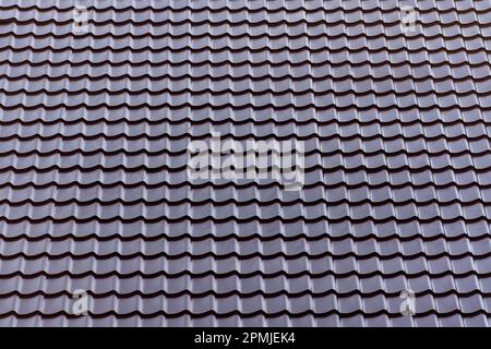 Roof of corrugated sheet. Brown corrugated metal profile roof installed on a modern house, close up. Roofing of metal profile wavy shape Stock Photo