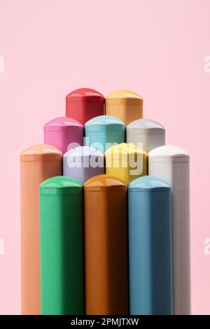 Colored pencils of pastel colors on a pink background. Abstract pyramid of pencils. Multi-colored pastel pencils. Stock Photo