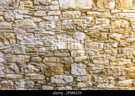 A wall of calcareous rubble stones displays its irregular texture in Omodos, Republic of Cyprus. The pale local limestone is a traditional building material in the region. Stock Photo