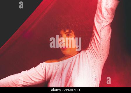 Portrait of a woman with red cloth stretched in front of her face. isolated on black background. Stock Photo