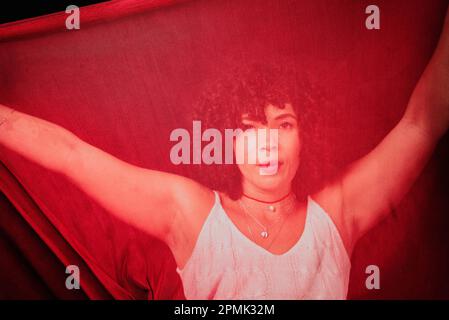 Portrait of a woman with red cloth stretched in front of her face. isolated on black background. Stock Photo