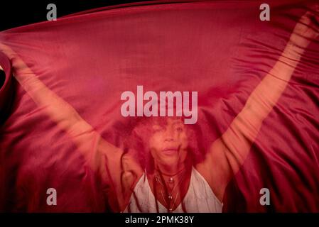 Portrait of a woman with red cloth stretched in front of her face. isolated on black background. Stock Photo