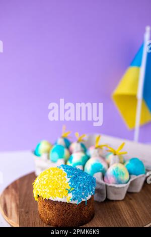 Easter cake decorated in colors of Ukrainian flag and eggs painted in yellow blue, laid out around it. easter concept, ukrainian traditions. Support U Stock Photo