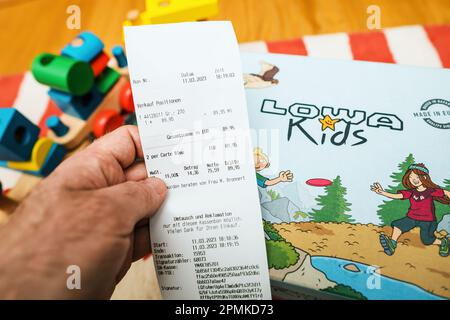 Frankfurt, Germany - Mar 12, 2023: Man holding paper receipt of the purchase for Lowa Kids insulated and waterproof shoes. Perfect for winter adventures Stock Photo