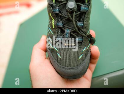 Frankfurt, Germany - Mar 12, 2023: POV male hand holding new Gore-Tex baby shoes high-quality German lowa shoes for unique outdoor experiences Stock Photo