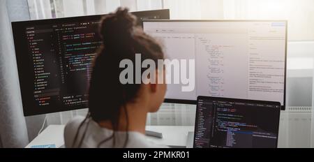 Back view of woman coding on computer, professional female programmer working in room Stock Photo