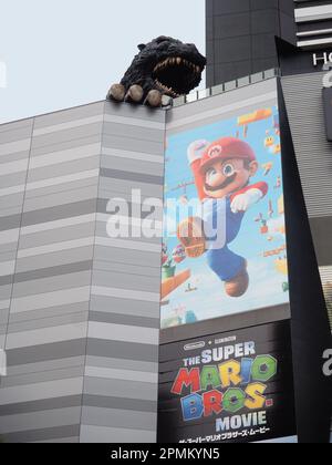 TOKYO, JAPAN - April 12, 2023: Statue of Godzilla on a Toho movie theater in Shinjuku which has a poster for The Super Mario Bros. Movie on it. Stock Photo