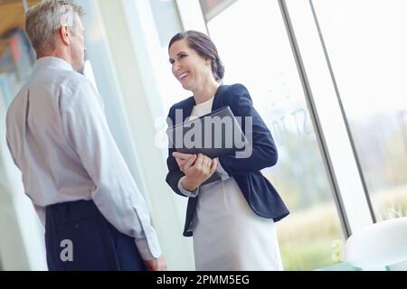 Having a quick catch up meeting. Two office workers standing together and having an informal meeting. Stock Photo