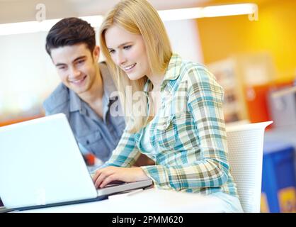 Working together to get the project done. Two smiling students helping each other with their homework. Stock Photo