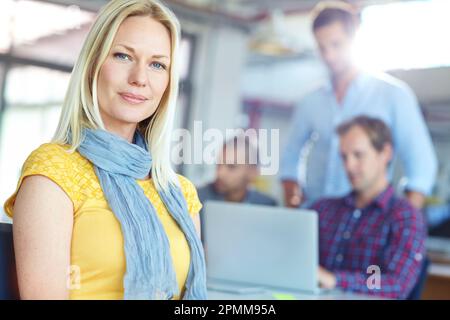 Dedicated to her team. Portrait of a young designer with colleagues in the background. Stock Photo