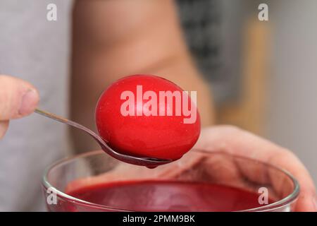 A man takes out colored Easter eggs from colored water. Dyeing easter eggs with food coloring is the first step in favorite Easter egg decorating idea Stock Photo