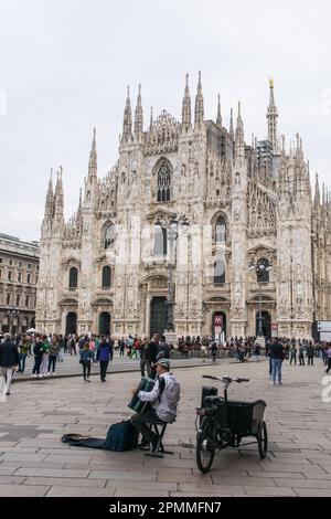 Tourists and an accordion player  beside Duomo di Milano , the famous Cathedral of milan, Piazza del Duomo. Stock Photo