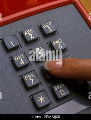 1992 HISTORICAL WOMAN’S FINGER PUSHING BUTTON KEYPAD ON RED AT&T CLASSIC TELEPHONE (©AT&T 1989) Stock Photo