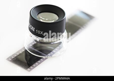 Isolated monochrome film and glass magnifier on white background. Stock Photo