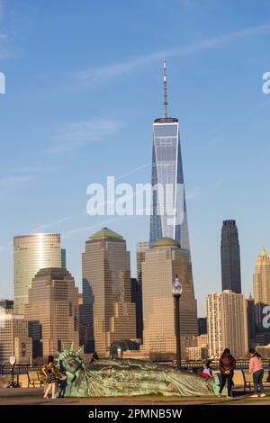 he sun sets on the 'Reclining Liberty' statue by artist Zaq Landsberg in Liberty State Park as it sits in front of the skyline of lower Manhattan and Stock Photo