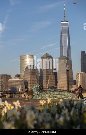 The sun sets on the 'Reclining Liberty' statue by artist Zaq Landsberg in Liberty State Park as it sits in front of the skyline of lower Manhattan and Stock Photo