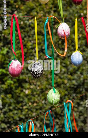 Painted eggs hang from the branches of the Easter tree. The focus is on a yellow egg painted by children by hand. High quality photo Stock Photo